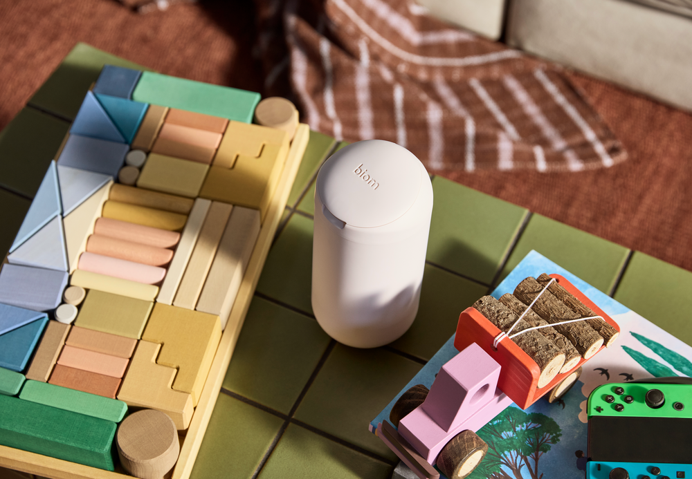Colorful building blocks on a table with a white device and a book in the background.